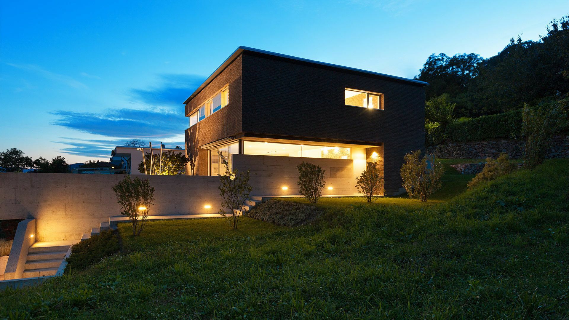 Modernes Einfamilienhaus am Abend mit effektvoller Innen- und Außenbeleuchtung